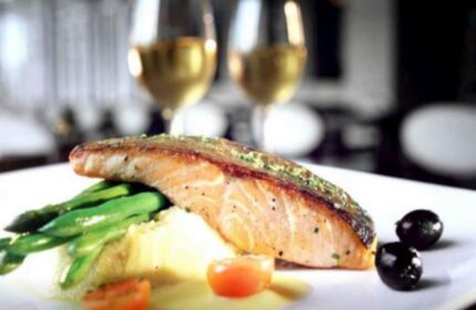 Fine dining at The Grove Suites by GRAND ASTON, a gay-friendly hotel. Salmon, asparagus, and wine create a luxurious experience.