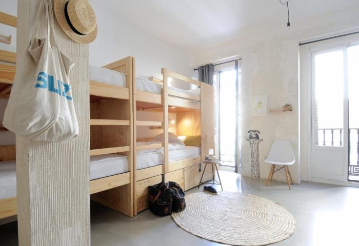 Dorm room at The Hat Hostel Madrid, a gay-friendly hotel. Bunk beds, bag, hat, and a round rug create a cozy, inviting space for travelers.