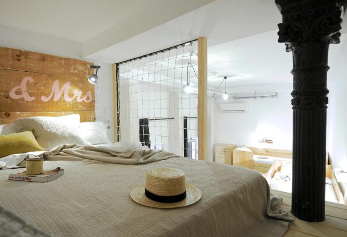 Gay-Friendly Hotel The Hat Hostel Madrid: Stylish room with rustic headboard, hat on bed. Perfect for gay travelers in Madrid, Spain.