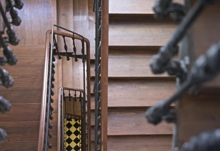 Staircase at The Hat Hostel, Madrid. Wood steps and ornate iron railings. Gay-friendly hotel with unique architectural details.