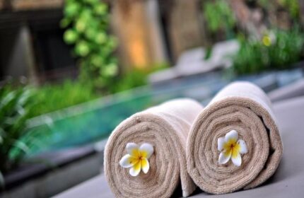 Rolled towels with frangipani flowers at The Haven Bali Seminyak, a gay-friendly hotel. Relaxing poolside scene in Seminyak, Bali.