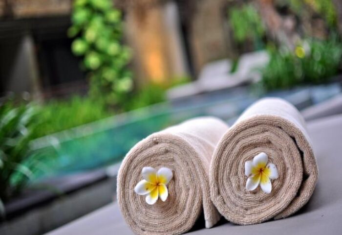 Rolled towels with frangipani flowers at The Haven Bali Seminyak, a gay-friendly hotel. Relaxing poolside scene in Seminyak, Bali.