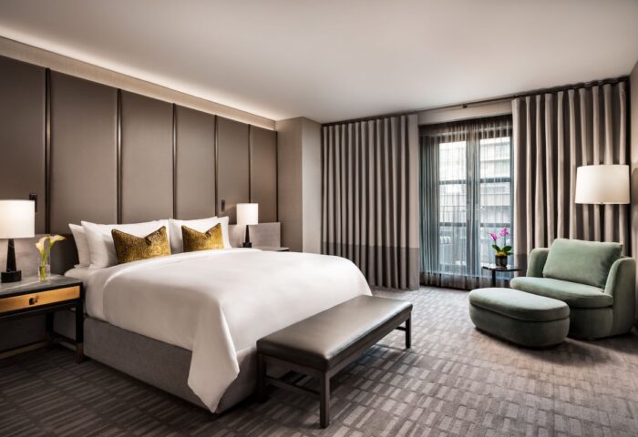 Hazelton Hotel's luxurious room. Gay-friendly hotel featuring a king bed, bench, armchair, and city view. Ideal for gay men's travel.