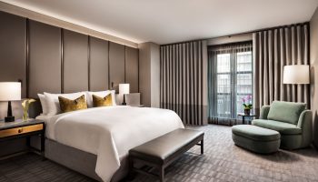 Hazelton Hotel's luxurious room. Gay-friendly hotel featuring a king bed, bench, armchair, and city view. Ideal for gay men's travel.