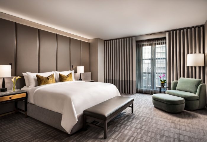 Hazelton Hotel's luxurious room. Gay-friendly hotel featuring a king bed, bench, armchair, and city view. Ideal for gay men's travel.