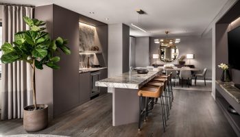 The Hazelton Hotel's gay-friendly suite: a marble counter with stools, a dining area, and a lush plant create a luxurious, welcoming space.