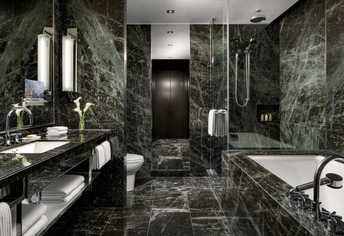 The Hazelton Hotel's luxurious bathroom. A gay-friendly hotel with marble walls, a soaking tub, and a walk-in shower. Upscale design for gay travelers.