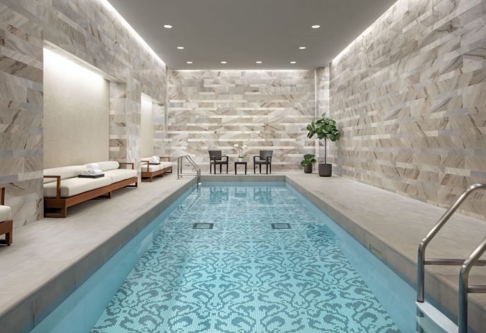 Indoor pool at The Hazelton Hotel, a gay-friendly hotel. The pool has a unique tile design. Chairs and lounges are nearby. Relaxing spa.