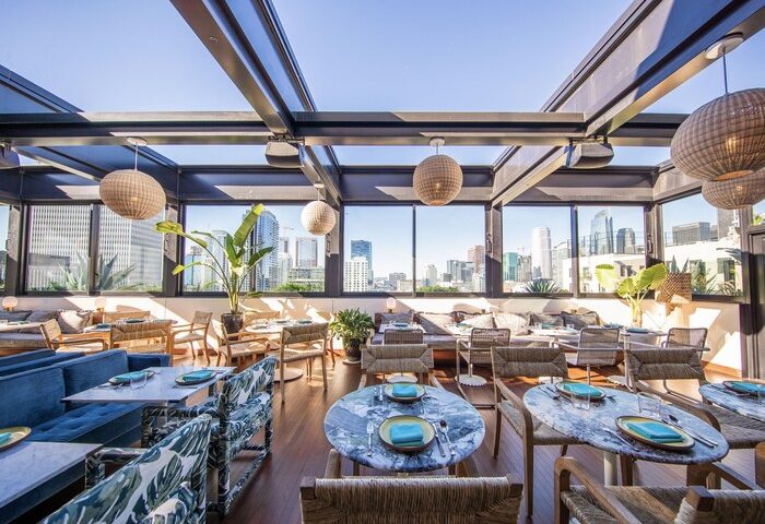 The Hoxton Downtown LA gay-friendly hotel rooftop restaurant. City view, tables, chairs, and plants. Great for gay travelers.