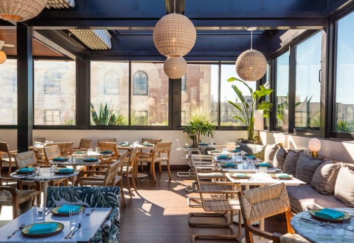 The Hoxton Downtown LA gay-friendly hotel's chic restaurant. Tables are set, natural light floods in, and plants add to the ambiance.