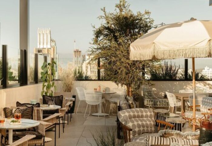 The Hoxton Downtown LA gay-friendly hotel rooftop patio. Outdoor seating with umbrellas, plants, and city views. Travel advice for gay men.