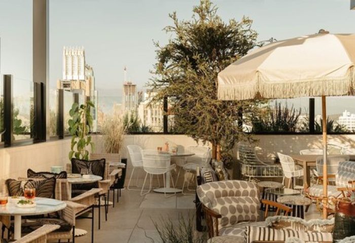 The Hoxton Downtown LA gay-friendly hotel rooftop patio. Outdoor seating with umbrellas, plants, and city views. Travel advice for gay men.