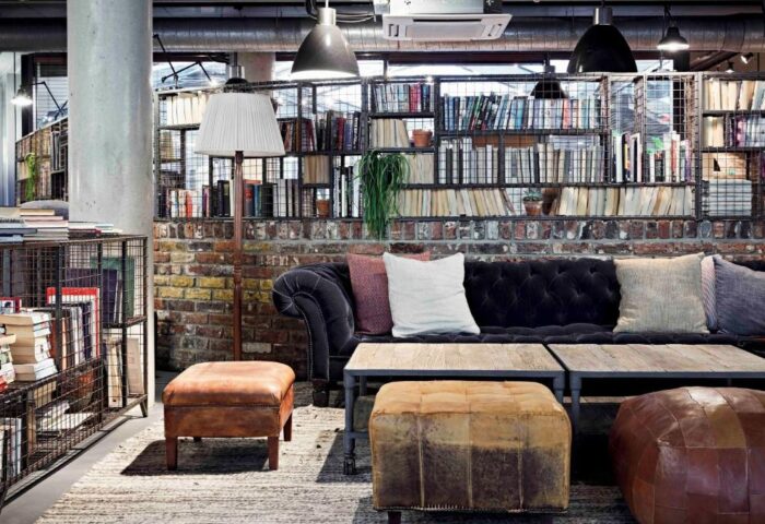 The Hoxton, Shoreditch: Stylish lounge area with a comfy couch, ottomans, and bookshelves. A gay-friendly hotel with a unique design.