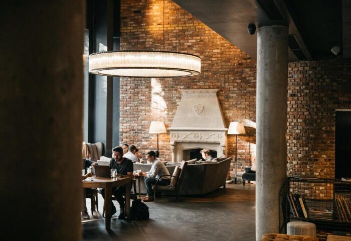 The Hoxton, Shoreditch: Chic lobby lounge with brick walls, fireplace, and people working. Gay-friendly hotel with stylish design.