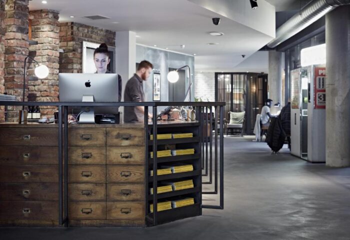 Reception area at The Hoxton, Shoreditch, a gay-friendly hotel. Staff at desk with vintage drawers. Modern, industrial design. London travel.