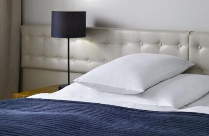 The Icon Hotel and Lounge bedroom. Gay-friendly hotel room with bed, pillows, headboard, and lamp. A comfortable space for gay travelers.