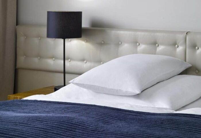 The Icon Hotel and Lounge bedroom. Gay-friendly hotel room with bed, pillows, headboard, and lamp. A comfortable space for gay travelers.