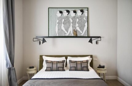 Bedroom at The Independent Suites, a gay-friendly hotel. Bed with pillows, bedside tables, lamps, and an art piece above the bed.