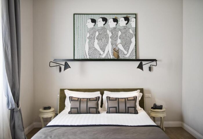 Bedroom at The Independent Suites, a gay-friendly hotel. Bed with pillows, bedside tables, lamps, and an art piece above the bed.