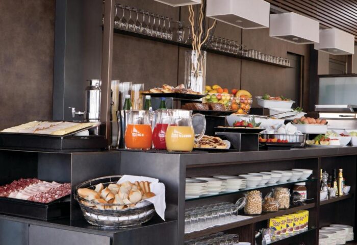 Breakfast buffet at The Independent Suites, a gay-friendly hotel. Features fresh juice, fruit, bread, meats, and pastries for a delicious morning meal.