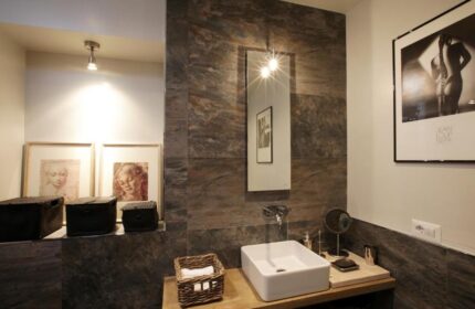 Gay-Friendly Hotel The Independent Suites bathroom. Modern design with stone tiles, square sink, mirror, and artwork. Gay travel accommodations.