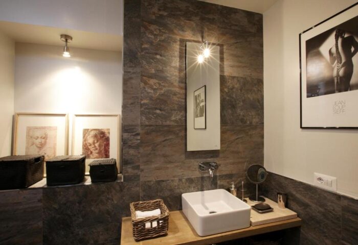 Gay-Friendly Hotel The Independent Suites bathroom. Modern design with stone tiles, square sink, mirror, and artwork. Gay travel accommodations.