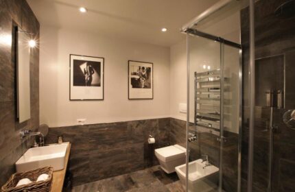 The Independent Suites gay-friendly hotel bathroom. Modern design with shower, toilet, bidet, sink, and black and white art.