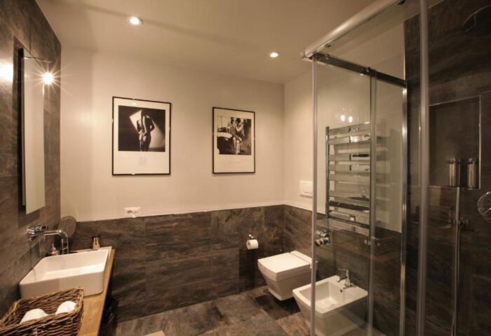 The Independent Suites gay-friendly hotel bathroom. Modern design with shower, toilet, bidet, sink, and black and white art.