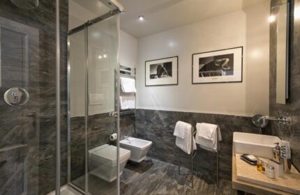 The Independent Suites gay-friendly hotel bathroom with shower, toilet, bidet, sink, and black and white art. Upscale design for gay travel.