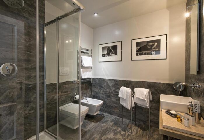 The Independent Suites gay-friendly hotel bathroom with shower, toilet, bidet, sink, and black and white art. Upscale design for gay travel.