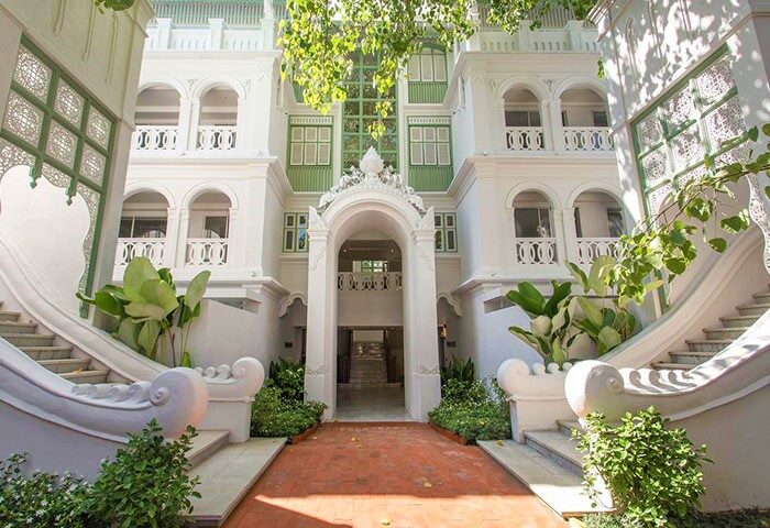 Facade of The Inside House, a gay-friendly hotel. White building with green accents, arched windows, and ornate staircases. Travel advice for gay men.