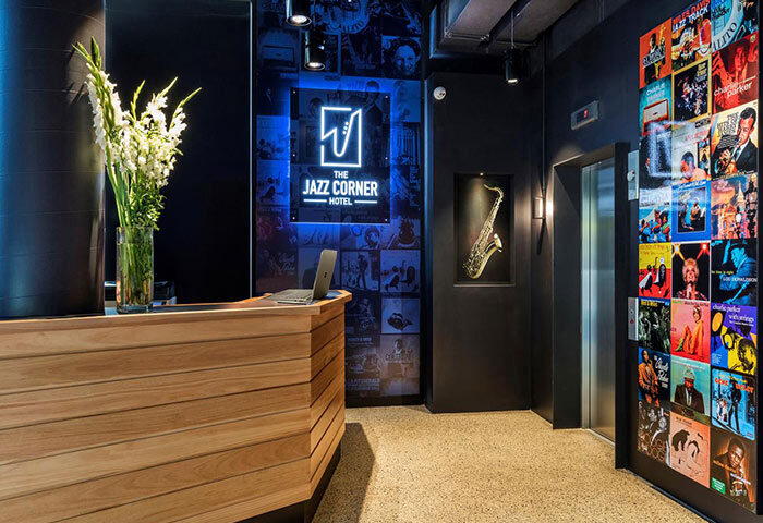 The Jazz Corner Hotel's stylish lobby. Gay-friendly hotel features a wood reception desk, jazz art, & saxophone decor. Great for gay travel.