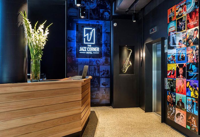 The Jazz Corner Hotel's stylish lobby. Gay-friendly hotel features a wood reception desk, jazz art, & saxophone decor. Great for gay travel.