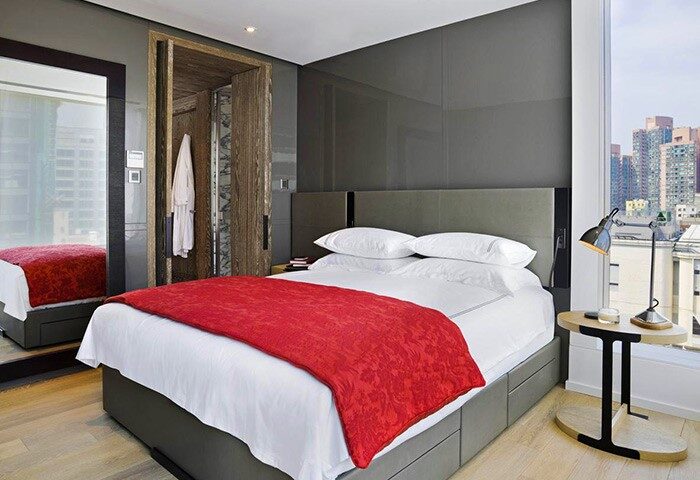 The Jervois gay-friendly hotel room. Modern design with red blanket on bed, city view, and closet. Luxury travel for gay men in Hong Kong.