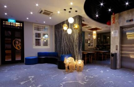 Interior of The Keong Saik Hotel, a gay-friendly hotel. Lobby with elephant statues, blue seating, and modern lighting. Stylish Singapore stay.