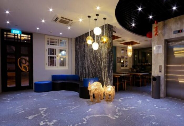 Interior of The Keong Saik Hotel, a gay-friendly hotel. Lobby with elephant statues, blue seating, and modern lighting. Stylish Singapore stay.