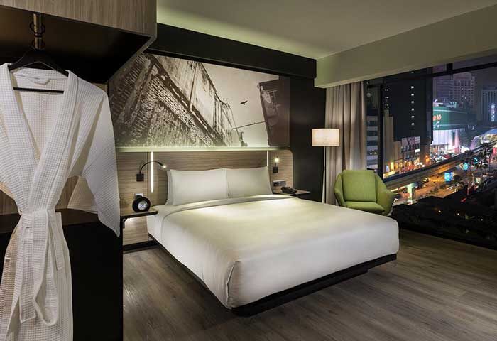 Kuala Lumpur Journal Hotel room. Gay-friendly hotel with city view. The Journal Hotel bedroom, robe, and city lights. Modern design.