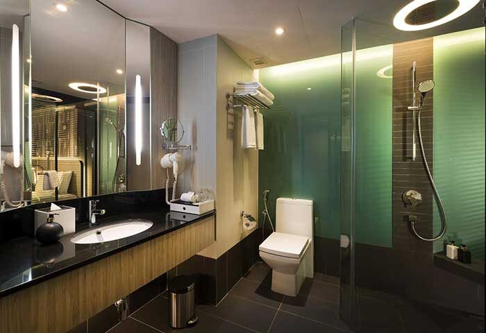 Bathroom at The Kuala Lumpur Journal Hotel, a gay-friendly hotel. Modern design with shower, toilet, sink, and large mirror. Ideal for gay travelers.