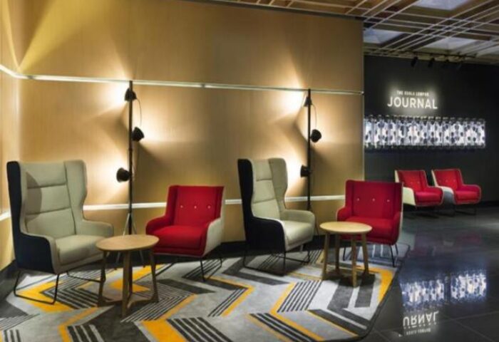 Lobby seating area at The Kuala Lumpur Journal Hotel, a gay-friendly hotel. Modern design with chairs, tables, and patterned carpet.