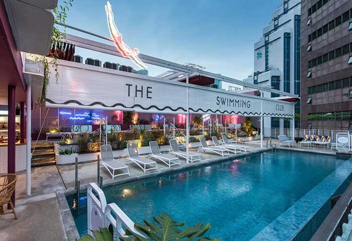 The Kuala Lumpur Journal Hotel's pool area. This gay-friendly hotel features The Swimming Club with lounge chairs and a diver neon sign.
