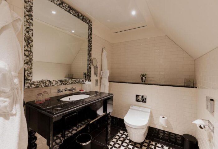 Bathroom at The Lalit London, a gay-friendly hotel. Black marble vanity and patterned floor tiles create a stylish design. Luxury travel.