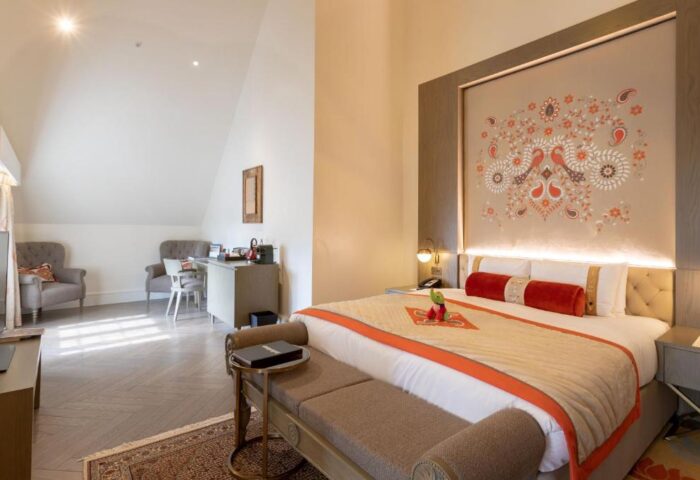 Gay-Friendly Hotel The Lalit London: Stylish bedroom with a large bed, desk, and seating area. A great choice for gay men's travel in London.