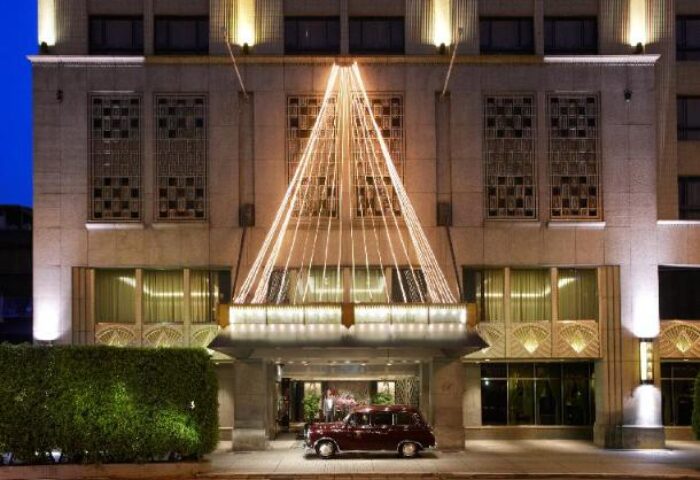 The Landis Taipei Hotel facade at night. Gay-friendly hotel with festive lights, classic car. Luxury travel for gay men in Taipei.
