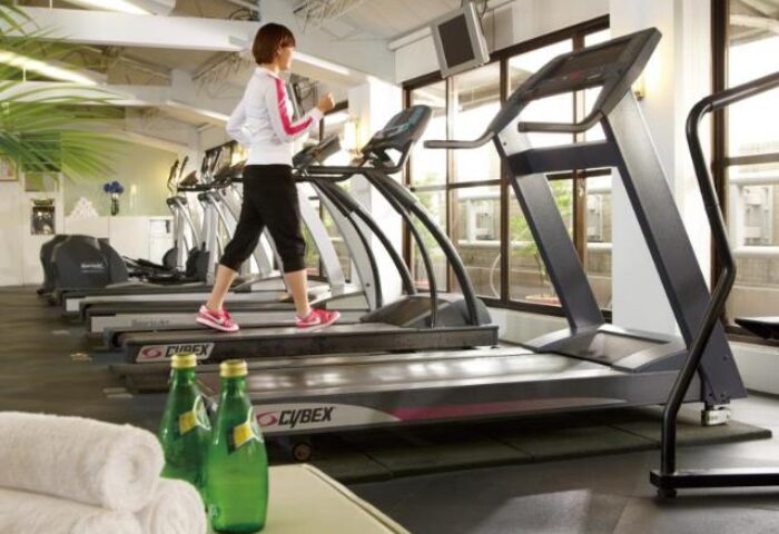The Landis Taipei Hotel gym. Woman on treadmill, towels, water. Gay-friendly hotel fitness center for gay men travelers in Taipei.