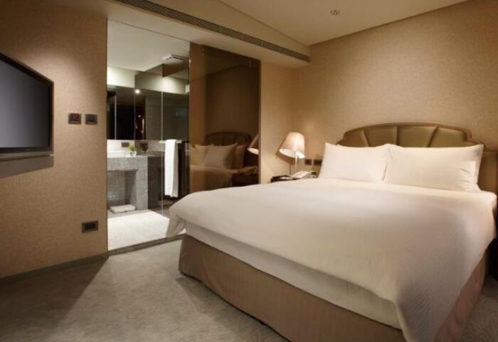 The Landis Taipei Hotel room. Gay-friendly hotel with a plush bed, TV, and bathroom view. Ideal for gay men's travel in Taipei.