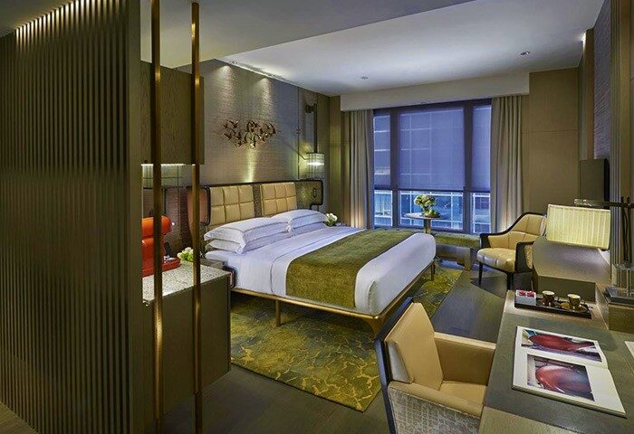 The Landmark Mandarin Oriental Hong Kong hotel room. Gay-friendly travel destination with a luxurious bed, desk, and city view.
