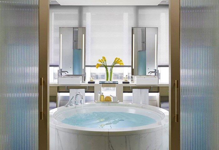 Bathroom at The Landmark Mandarin Oriental Hong Kong, a gay-friendly hotel. Round tub, double sinks, and modern design offer luxury.