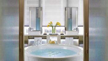 Bathroom at The Landmark Mandarin Oriental Hong Kong, a gay-friendly hotel. Round tub, double sinks, and modern design offer luxury.