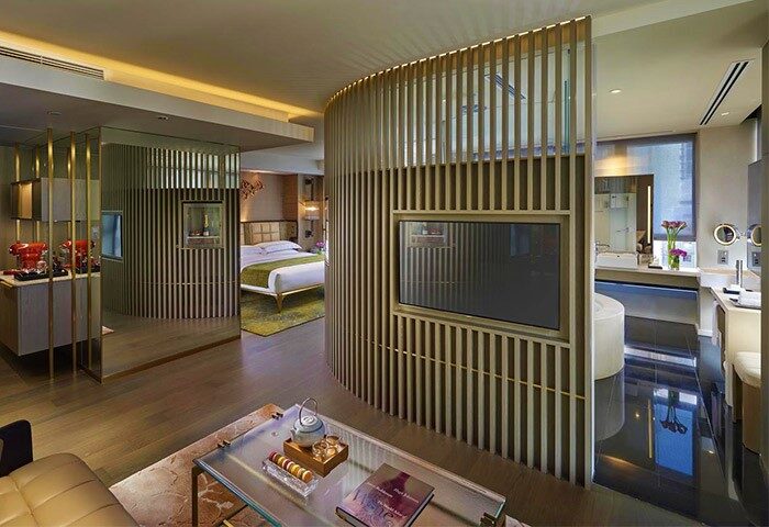 The Landmark Mandarin Oriental Hong Kong gay-friendly hotel suite. View of the bedroom, bathroom, and living room with a glass table.