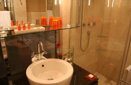 Bathroom at The Levante Parliament, a gay-friendly design hotel. Sink, shower, and orange accents create a stylish, adults-only space.